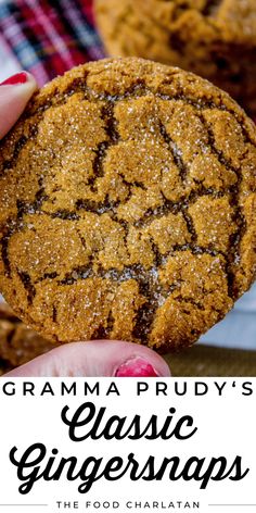 a close up of a person holding a cookie in their hand with the text grandma prudy's classic ginger snaps