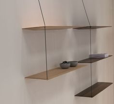 three wooden shelves hanging from the side of a wall with two bowls on each shelf