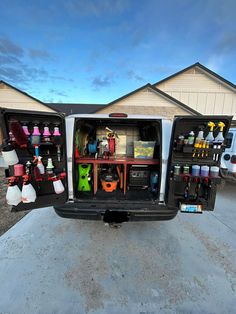 the back end of a white truck with its doors open and various items in it