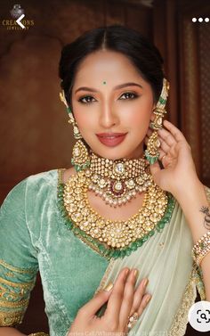 a woman wearing a green and gold outfit with jewelry on her neck, posing for the camera