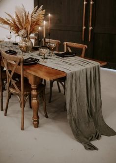 a wooden table topped with a vase filled with flowers next to a couple of chairs