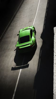 a green sports car is parked on the side of the road in an empty parking lot