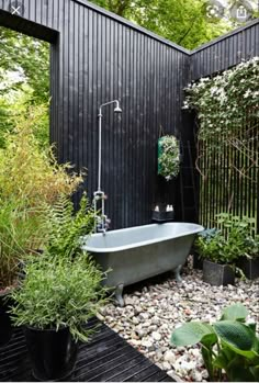 an outdoor bathtub in the middle of a garden with lots of plants around it