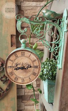 a clock hanging from the side of a brick wall next to a potted plant