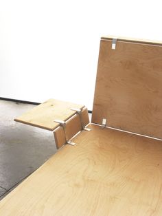 a wooden bench sitting on top of a cement floor next to a white wall and door