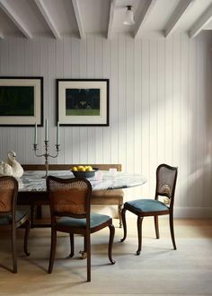 a dining room table with chairs and two pictures on the wall above it, along with other furniture