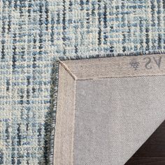 the corner of a rug with a blue and white checkered pattern on it, next to a wooden floor