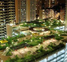 an aerial view of a city at night with lots of buildings and trees in the foreground