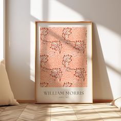 an orange and pink wall hanging next to a white pillow on top of a wooden floor