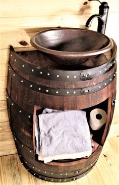 a wooden barrel with a sink and toilet paper on the bottom is next to a towel rack