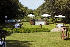 tables and umbrellas are set up on the lawn for an outdoor wedding reception in the woods