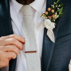 a close up of a person wearing a suit and tie with a boutonniere on his lapel