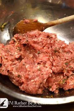 ground meat being cooked in a metal bowl with a wooden spoon on the counter top