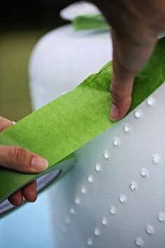 a person is cutting paper on top of a green object with water droplets all over it