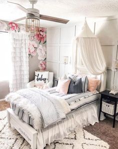 a bedroom with a white bed and pink flowers on the wall