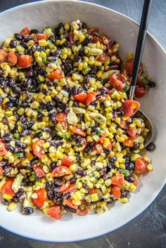 corn salad with black beans and tomatoes in a white bowl