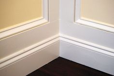 the corner of a room with white walls and wood flooring is painted in yellow