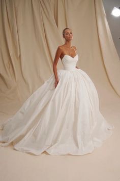 a woman in a white wedding dress posing for a photo with her hands on her hips