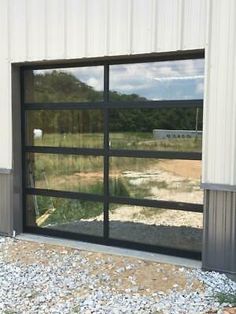 an open garage door on the side of a building with gravel in front of it