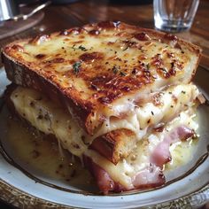 a close up of a plate of food with cheese and ham on it, next to a glass of water