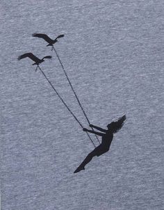 two birds are flying in the sky and one is holding on to a woman's string