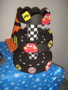 a three tiered cake with cars on it's sides and stars in the background