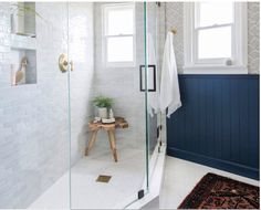 a bathroom with white tile and blue accenting the walls, along with a glass shower door