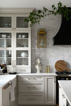 a kitchen with white cabinets and marble counter tops, gold trim on the glass doors