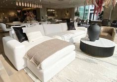 a living room filled with white furniture and lots of pillows on top of it's couches