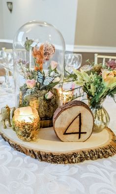 the table is set with candles and flowers in glass vases on top of wood slices