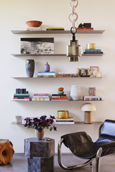 a living room filled with furniture and bookshelves next to a wall mounted shelf