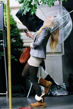 a woman holding an umbrella and using her cell phone