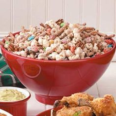 a red bowl filled with food next to two bowls of dip and other foods on a table