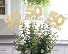 a vase filled with white flowers sitting on top of a table next to a sign that reads 50 reunion