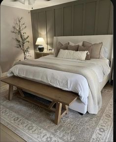 a bedroom with a bed, bench and lamp on the side table in front of it