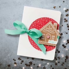 a card with a gingerbread house on it and green ribbon tied around the edge