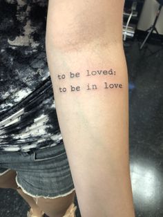 a person with a tattoo on their arm that says to be loved, to be in love