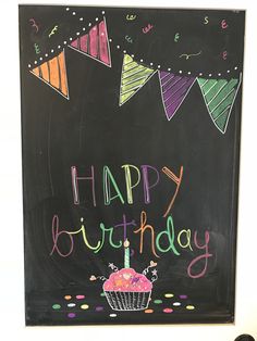 a chalkboard with the words happy birthday written on it in front of a cupcake