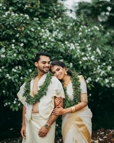 two people standing next to each other in front of trees