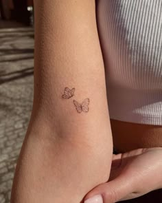 a woman's arm with two small butterflies on the left side of her arm