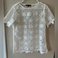 white crochet top hanging on the wall in front of a door with clothes hanger