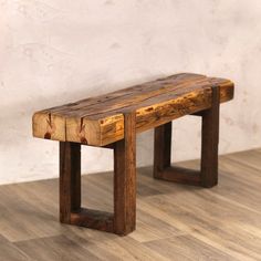 a wooden bench sitting on top of a hard wood floor next to a white wall