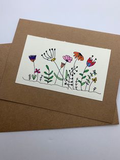 a greeting card with flowers and butterflies on it, sitting on top of a brown envelope