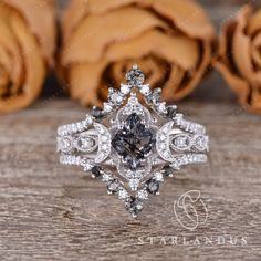 a black and white diamond ring sitting on top of a wooden table next to roses