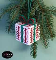 a christmas ornament hanging from a pine tree with a red and green ribbon