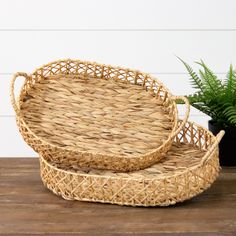 two wicker trays sitting on top of a wooden table next to a potted plant