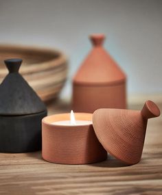 a candle sitting on top of a wooden table next to two vases and plates