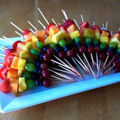 a blue plate topped with lots of fruit on top of a wooden table next to a phone