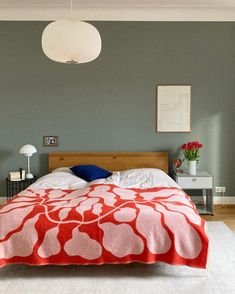 a bed with a red and white comforter on top of it in a bedroom