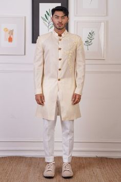 Cream long sherwani with gold buttons, elevated with tonal and placement floral embroidery. Paired with a pant. - Aza Fashions Elegant Long Sleeve Sherwani With Gota Work, Elegant Ceremonial Bandhgala With Gota Work, Ceremonial Sherwani With Gota Work And Long Sleeves, Long Sleeve Sherwani With Gota Work For Ceremonial Occasions, Ceremonial Long Sleeve Sherwani With Gota Work, Elegant Sherwani With Gota Work For Ceremonial Occasions, Designer Bandhgala With Gota Work For Eid, Fitted Long Sleeve Sherwani With Gota Work, Straight Kurta Sherwani With Gota Work For Reception